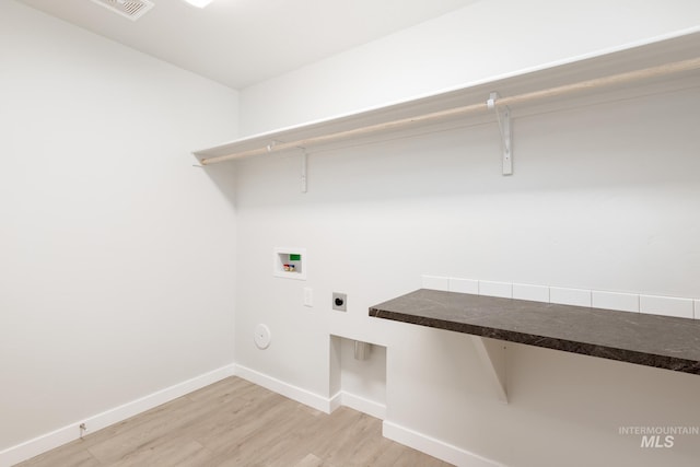 clothes washing area featuring hookup for a washing machine, baseboards, light wood finished floors, hookup for an electric dryer, and laundry area