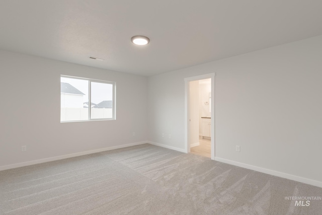 empty room with visible vents, baseboards, and light colored carpet