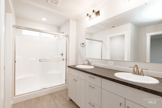 bathroom featuring a sink, visible vents, wood finished floors, and a stall shower