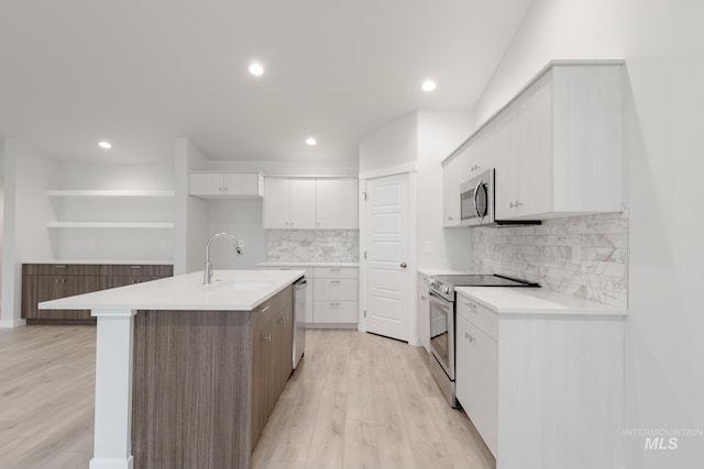 kitchen with light wood-style flooring, a sink, light countertops, appliances with stainless steel finishes, and white cabinetry