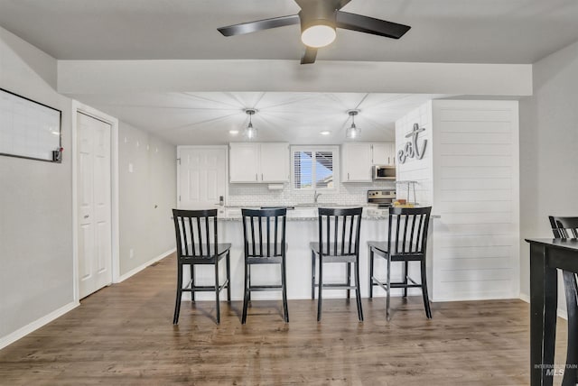 275 Elaine Ave Unit 2, Twin Falls, ID 83301 - kitchen featuring appliances with stainless steel finishes, a peninsula, white cabinetry, decorative backsplash, and a kitchen bar