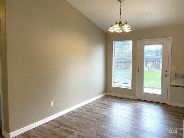 228 W Winnipeg St, Meridian, ID 83642 - unfurnished dining area with plenty of natural light, a chandelier, wood finished floors, a textured wall, and vaulted ceiling