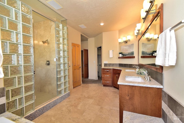 full bathroom with vanity, a textured ceiling, and walk in shower