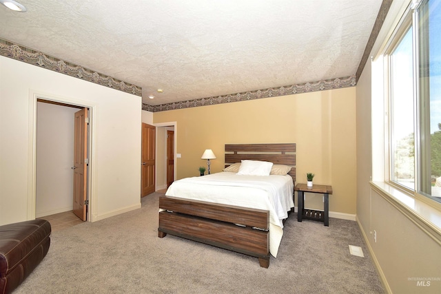 bedroom featuring a textured ceiling, multiple windows, and light carpet
