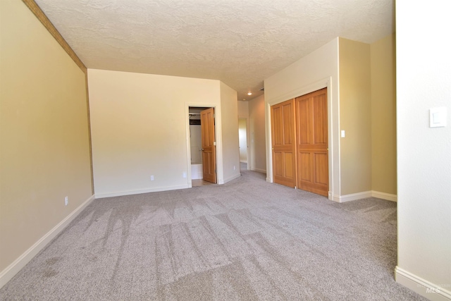 unfurnished bedroom featuring light carpet, a textured ceiling, and baseboards