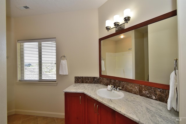 bathroom featuring vanity, baseboards, tile patterned floors, walk in shower, and visible vents