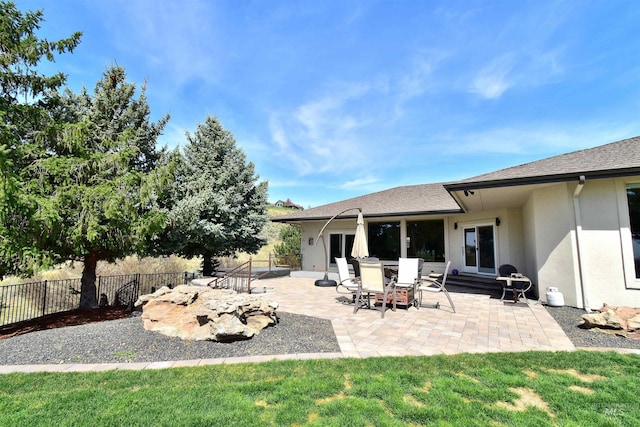 exterior space with a patio, stucco siding, fence, and a lawn