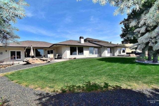 back of property featuring a yard, a patio area, and a chimney
