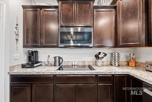 1430 NE Quigley St, Mountain Home, ID 83647 - kitchen with light countertops, black electric stovetop, stainless steel microwave, and dark brown cabinets