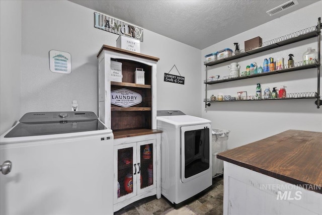 1430 NE Quigley St, Mountain Home, ID 83647 - laundry area featuring laundry area, a textured ceiling, stone finish floor, visible vents, and washer and clothes dryer