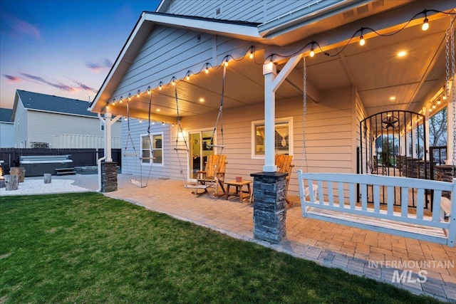 1430 NE Quigley St, Mountain Home, ID 83647 - back of house at dusk with a lawn, a patio area, fence, and a hot tub