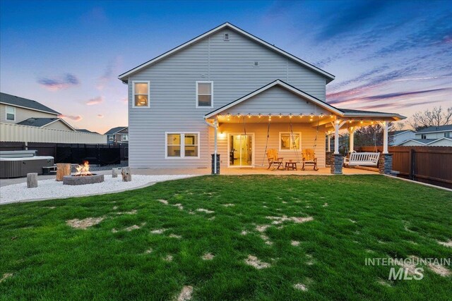 1430 NE Quigley St, Mountain Home, ID 83647 - back of property at dusk with a patio, fence, and a lawn