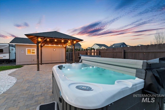 1430 NE Quigley St, Mountain Home, ID 83647 - pool at dusk featuring a gazebo, a patio, fence, and a hot tub