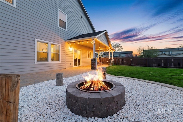 1430 NE Quigley St, Mountain Home, ID 83647 - patio terrace at dusk featuring fence, a fire pit, and a lawn