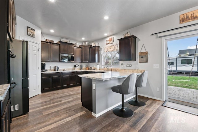 1430 NE Quigley St, Mountain Home, ID 83647 - kitchen featuring a peninsula, wood finished floors, stainless steel microwave, and dark brown cabinetry
