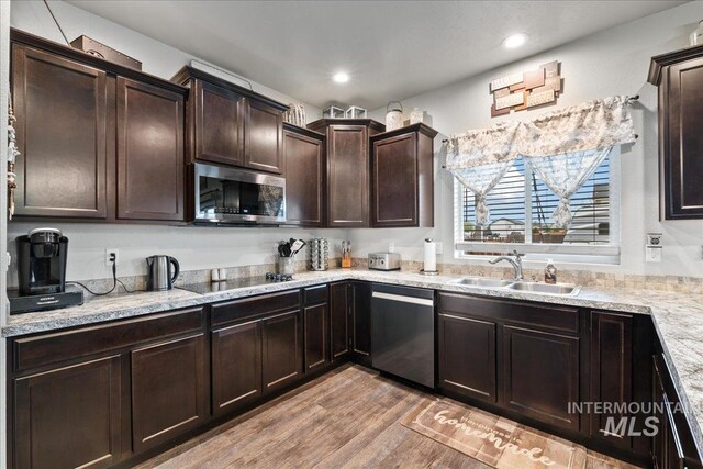 1430 NE Quigley St, Mountain Home, ID 83647 - kitchen featuring a sink, appliances with stainless steel finishes, dark brown cabinets, light stone countertops, and light wood-style flooring