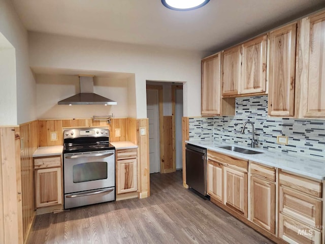 kitchen with light brown cabinets, sink, wall chimney range hood, stainless steel appliances, and hardwood / wood-style flooring