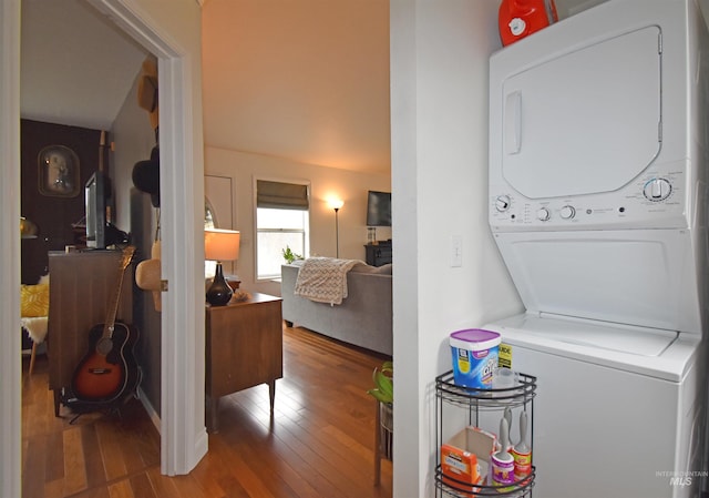 laundry room with laundry area, hardwood / wood-style flooring, and stacked washer and dryer