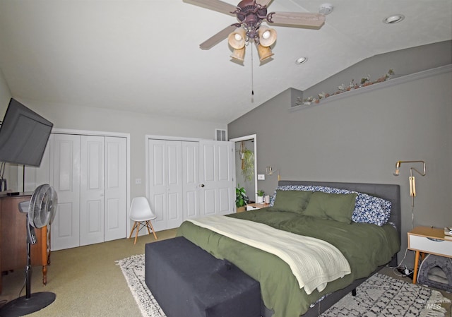 bedroom featuring multiple closets, carpet, lofted ceiling, and a ceiling fan