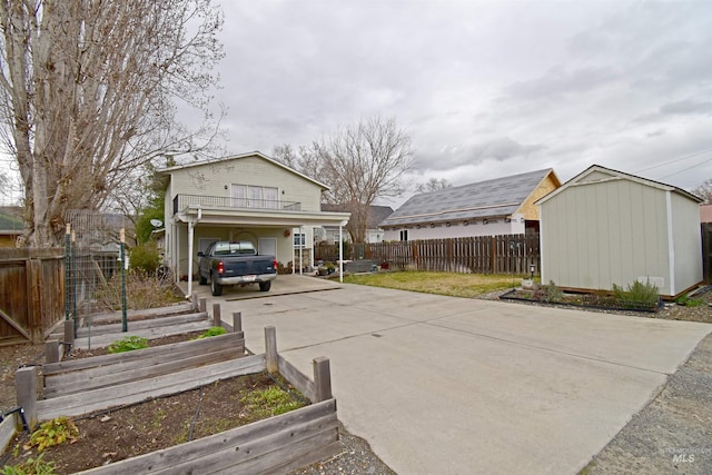 exterior space featuring fence, a shed, a vegetable garden, concrete driveway, and an outdoor structure