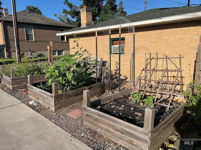 view of side of property with brick siding, cooling unit, a chimney, and a garden