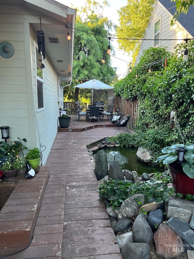 deck with visible vents, outdoor dining area, and fence