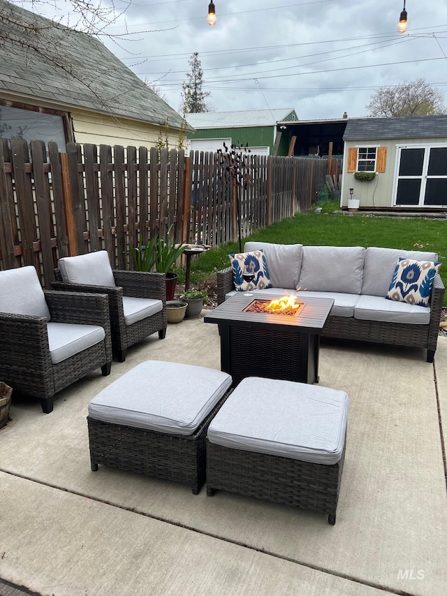 view of patio / terrace featuring an outbuilding, an outdoor living space with a fire pit, and fence