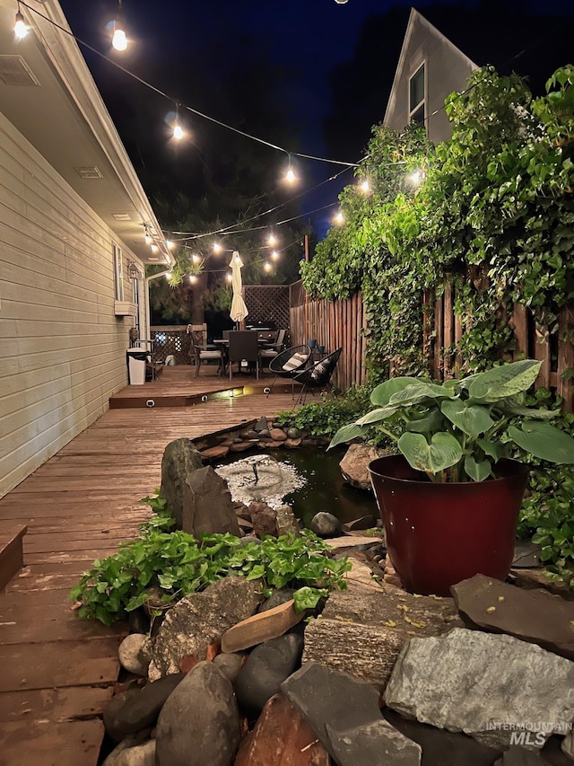 deck at twilight with visible vents and fence