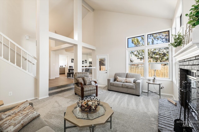 carpeted living room with a brick fireplace, baseboards, stairs, beam ceiling, and high vaulted ceiling