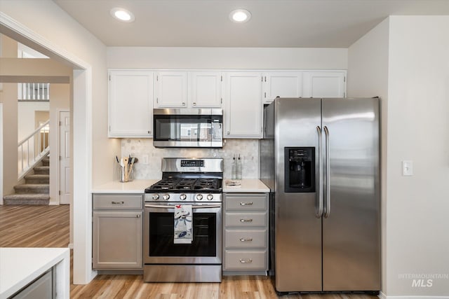 kitchen featuring recessed lighting, decorative backsplash, light countertops, appliances with stainless steel finishes, and light wood-type flooring