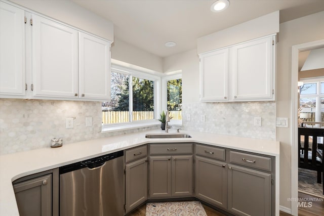 kitchen featuring stainless steel dishwasher, light countertops, gray cabinets, and a sink