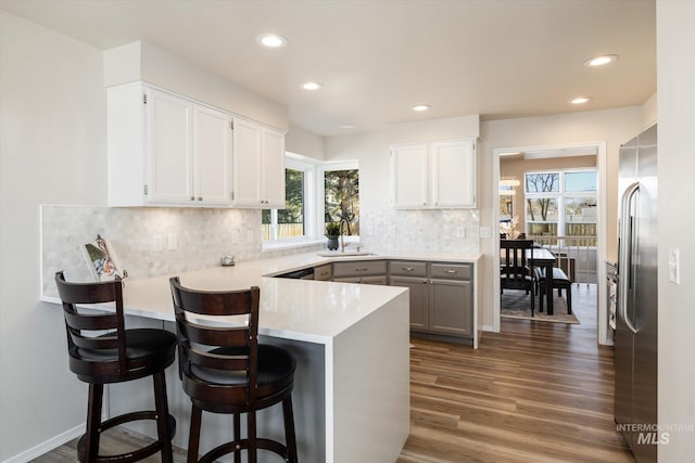 kitchen with high quality fridge, a peninsula, wood finished floors, and white cabinets