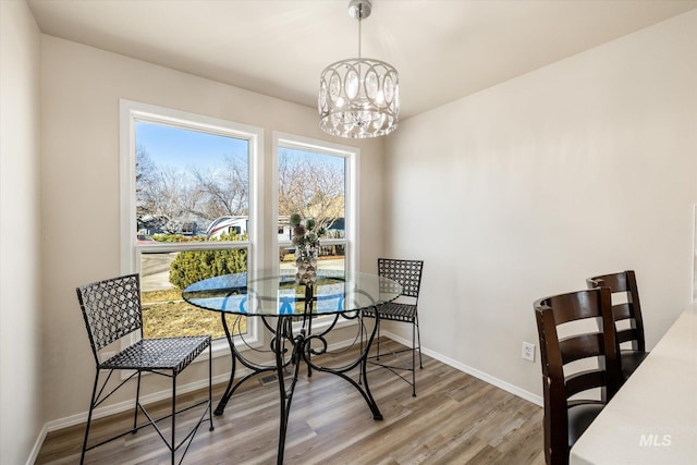 dining area with baseboards, an inviting chandelier, and wood finished floors