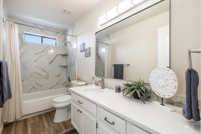 bathroom featuring visible vents, toilet, shower / tub combo with curtain, wood finished floors, and vanity