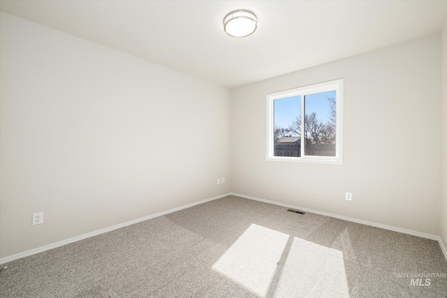 carpeted spare room with visible vents and baseboards