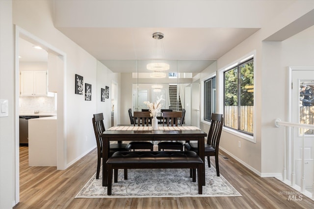 dining area with baseboards, light wood finished floors, and a chandelier