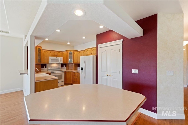 25090 The Driving Ln, Caldwell, ID 83607 - kitchen featuring white appliances, light wood finished floors, glass insert cabinets, light countertops, and recessed lighting