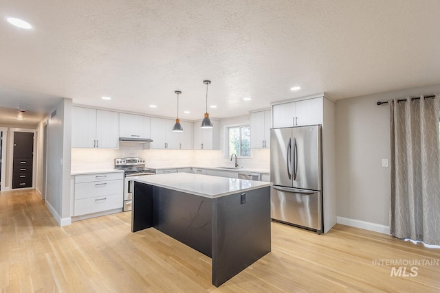 kitchen with white cabinets, pendant lighting, stainless steel appliances, and a kitchen island