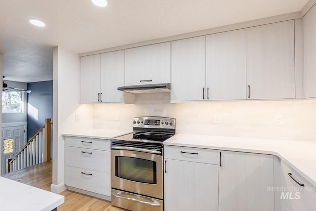 kitchen with backsplash, light hardwood / wood-style flooring, white cabinets, and stainless steel electric range