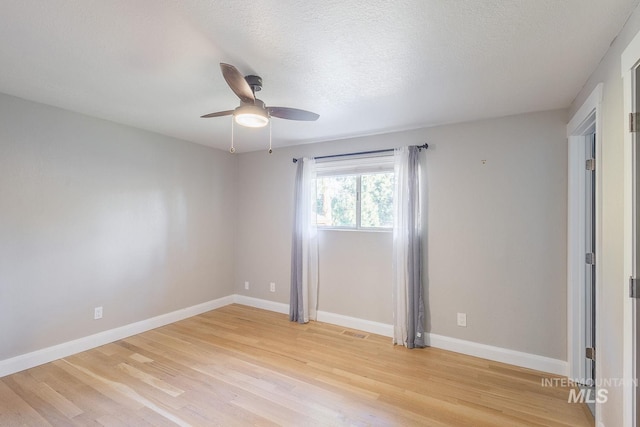 spare room with a textured ceiling, light hardwood / wood-style floors, and ceiling fan