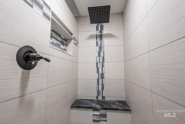 bathroom with a tile shower and tile walls