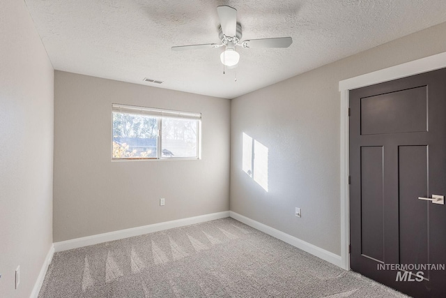 carpeted spare room with ceiling fan and a textured ceiling