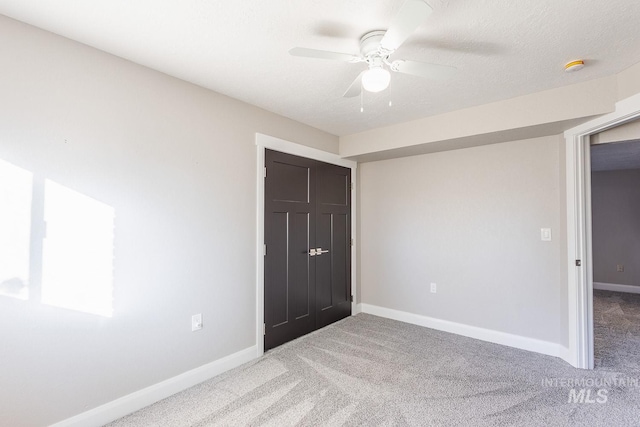 unfurnished bedroom with carpet, a closet, and ceiling fan