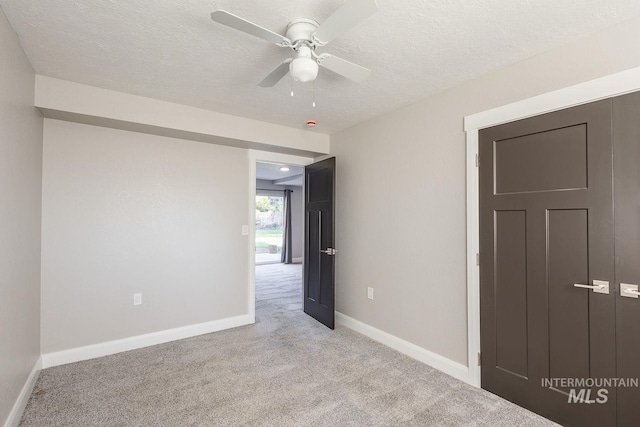 empty room with a textured ceiling, ceiling fan, and light carpet