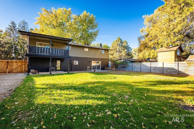 back of property with a patio area, a balcony, and a yard