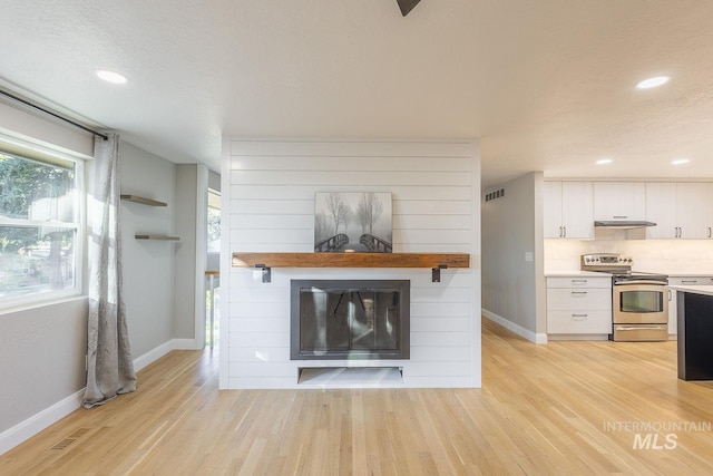 unfurnished living room featuring a fireplace, light hardwood / wood-style floors, and a textured ceiling