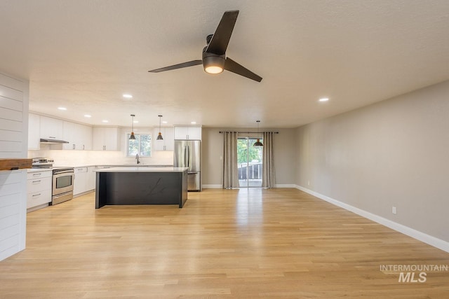 kitchen with stainless steel appliances, a kitchen island, light hardwood / wood-style flooring, decorative light fixtures, and white cabinets