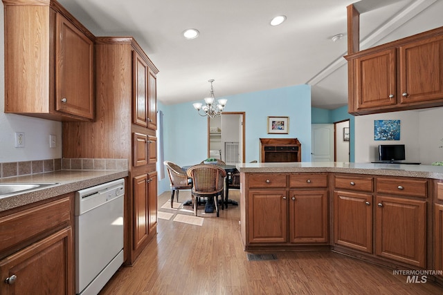1320 American Ln, Emmett, ID 83617 - kitchen with white dishwasher, brown cabinets, a chandelier, light wood finished floors, and recessed lighting