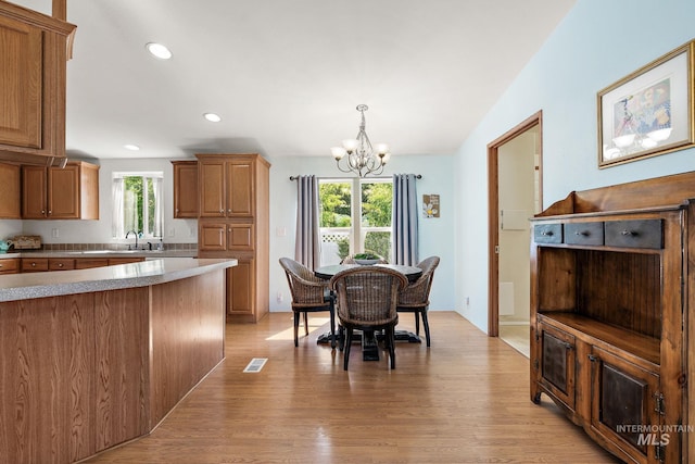 1320 American Ln, Emmett, ID 83617 - kitchen with a chandelier, light countertops, brown cabinets, a sink, and light wood finished floors