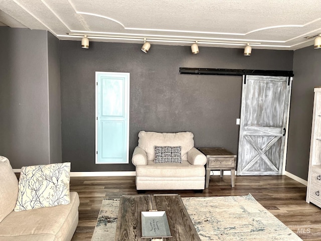 living area with rail lighting, dark hardwood / wood-style floors, a barn door, and a textured ceiling